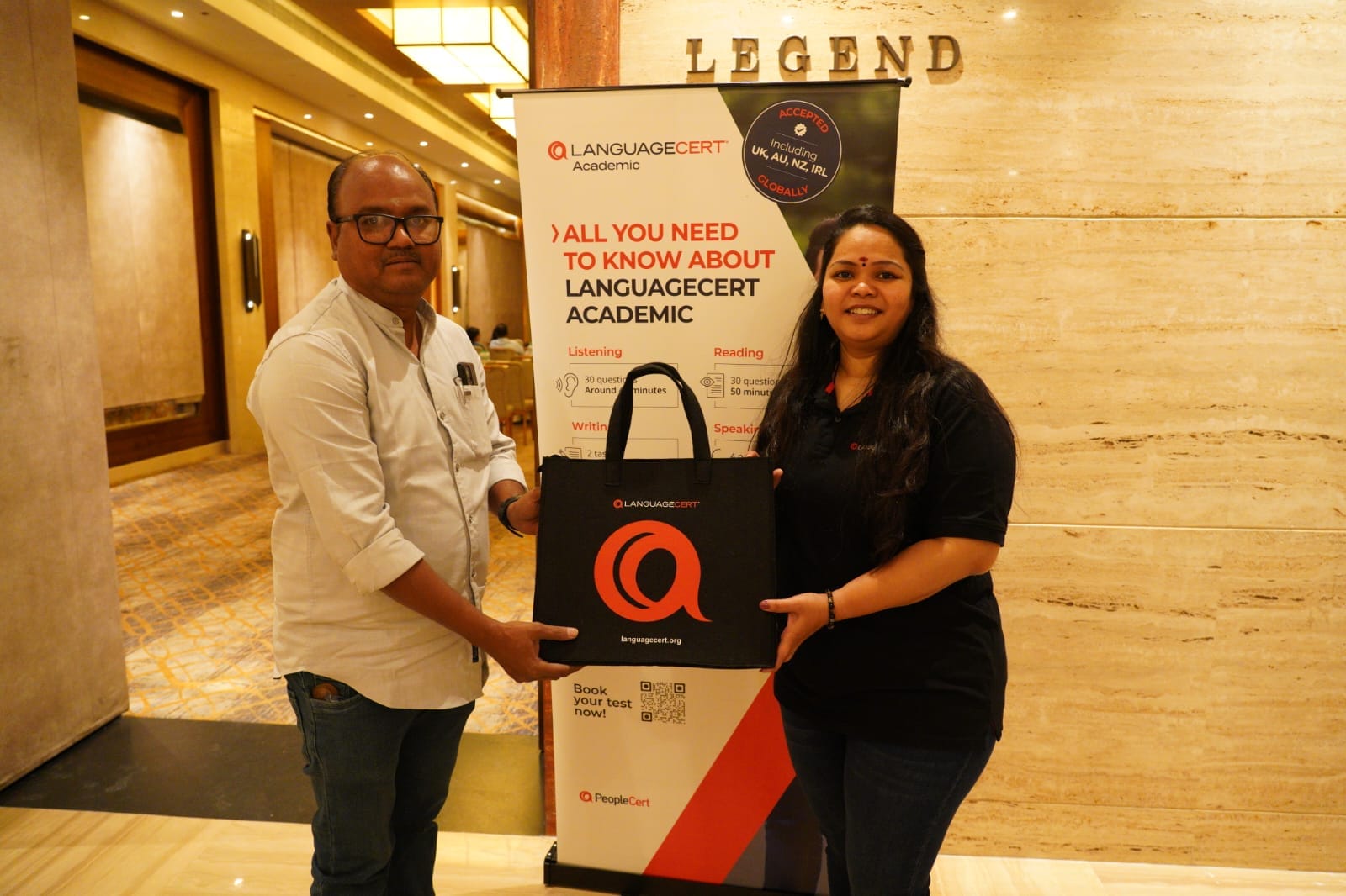 Two people holding a LanguageCert bag beside a LanguageCert Academic banner